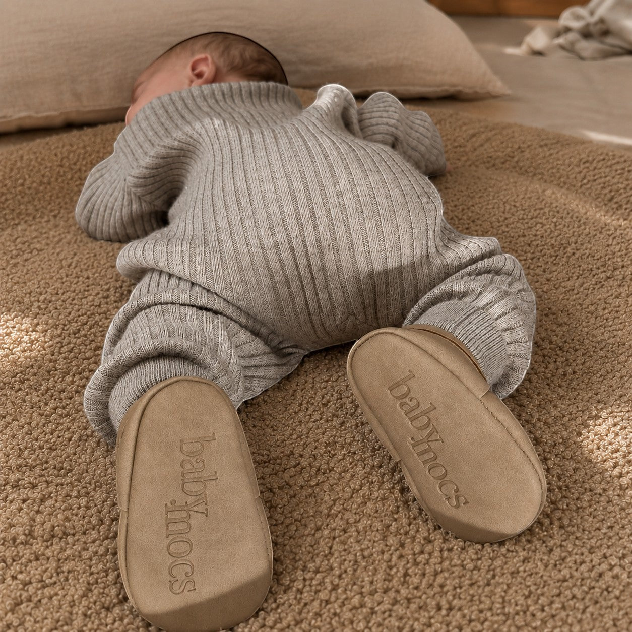 BabyMocs casual mocs i greige med mjuk sula på en bebis som ligger på en mjuk matta